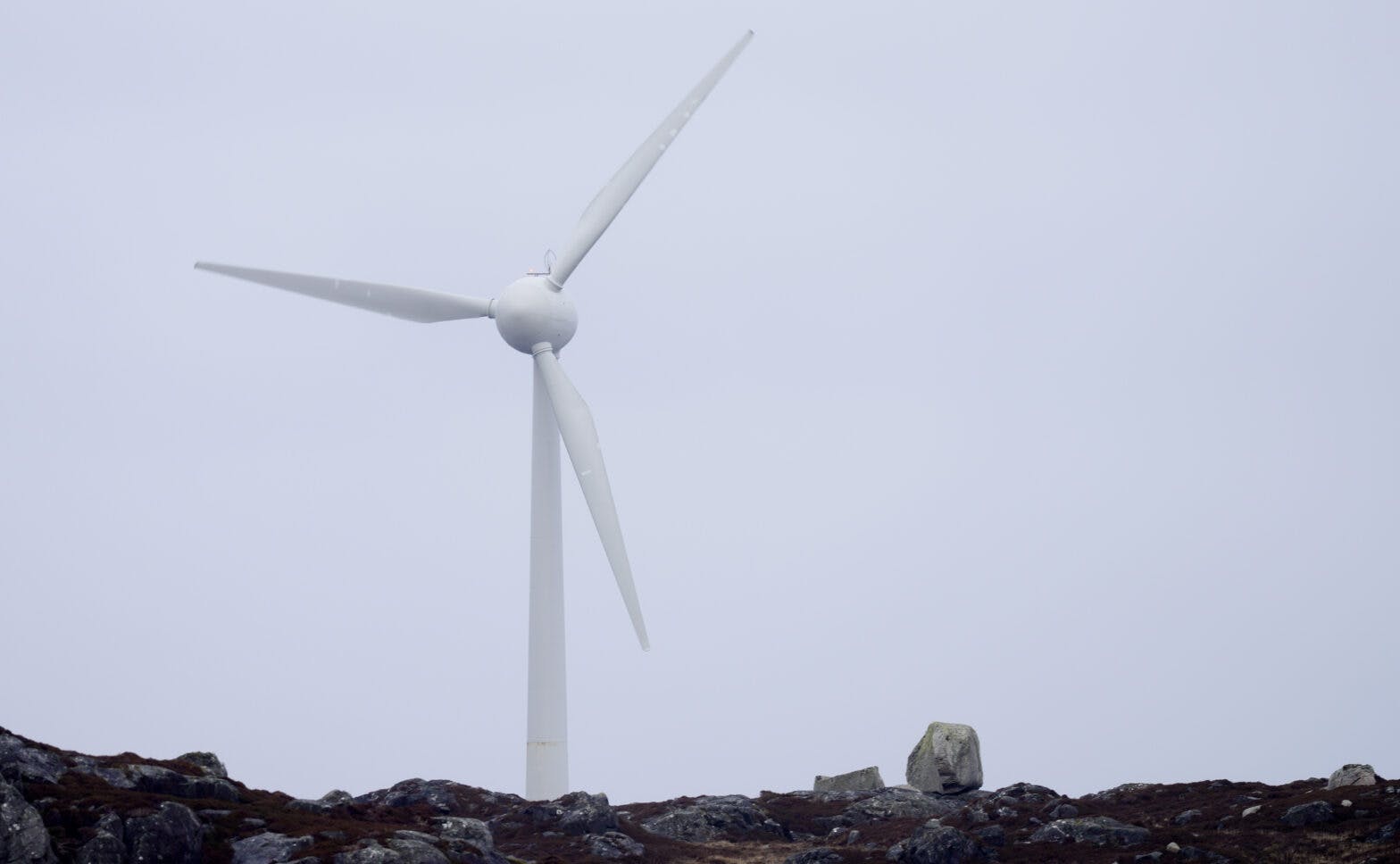En vindturbin sitter på toppen av en steinete bakke.