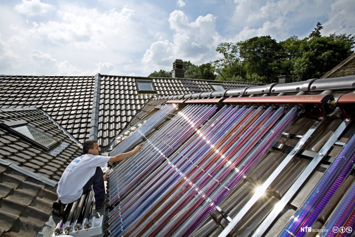 Mann monterer solfanger på tak